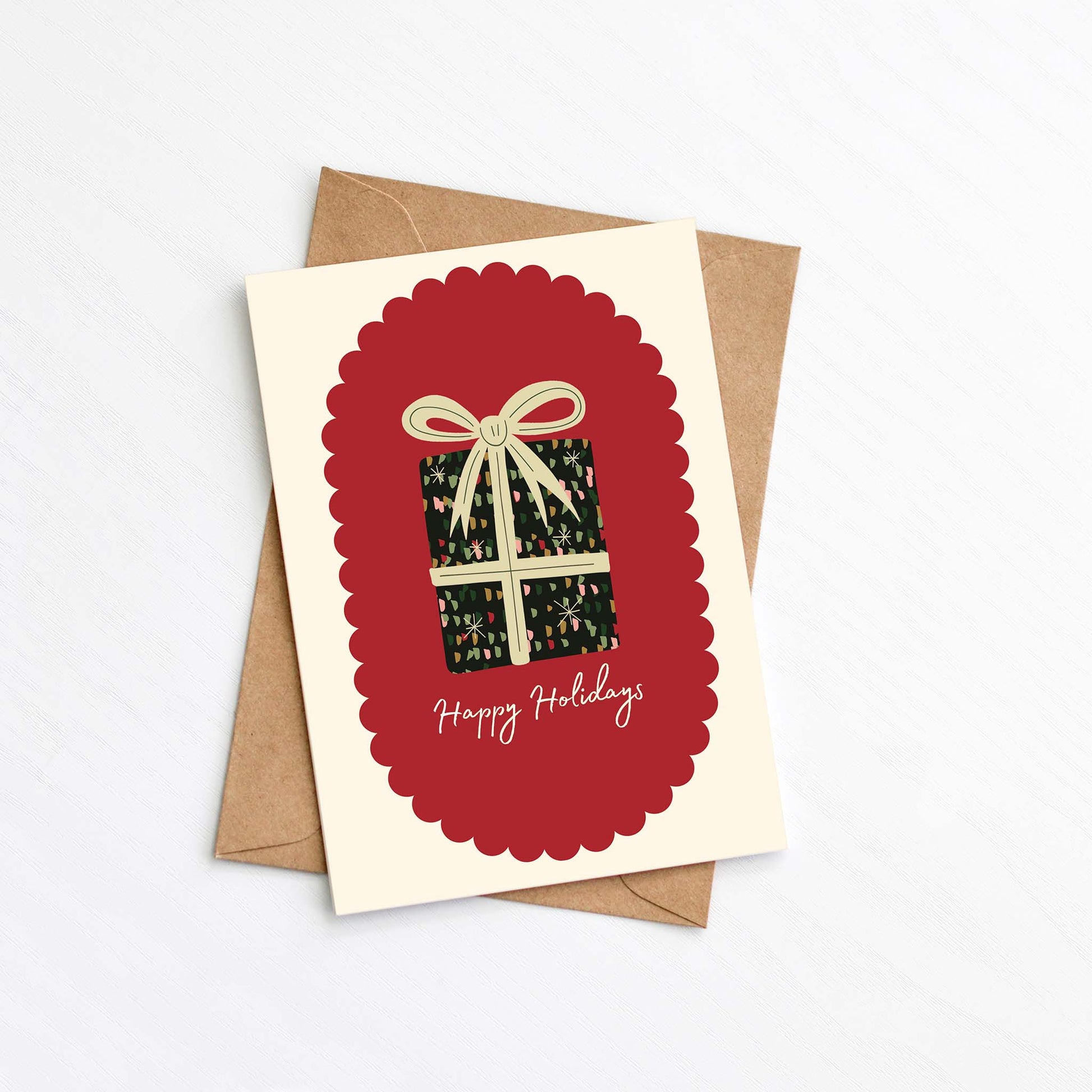 Happy Holidays Christmas card with colourful present illustration, red scalloped frame, and brown envelope