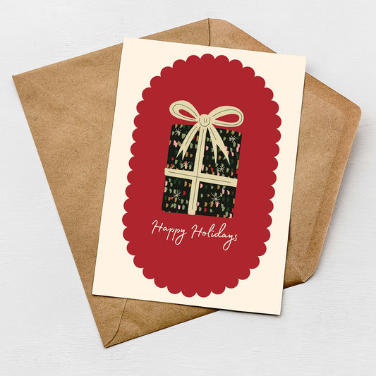 Happy Holidays Christmas card with gift box design, red scalloped frame, and brown envelope